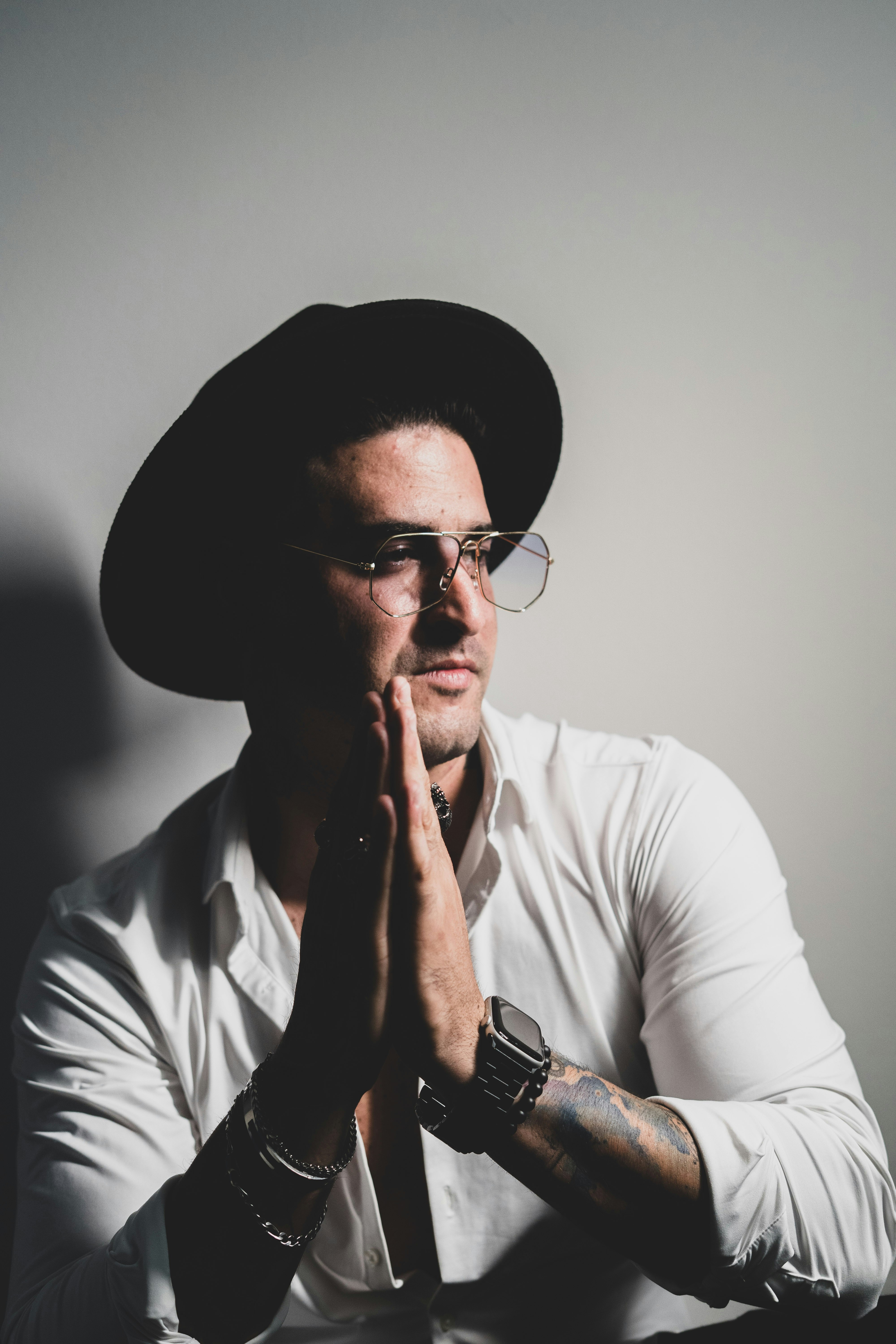 man in white dress shirt wearing black fedora hat and black framed eyeglasses